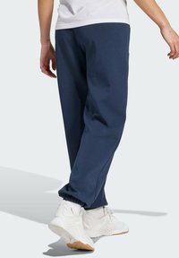 Navyblauwe sweatpants gemaakt van zachte stof, met elastische boorden en een relaxte pasvorm. Gepaard met witte sportschoenen voor contrast.