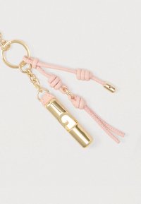 Kullatooni metallist kapsli ripats roosade nahknööride ja -sõlmedega, kinnitatud metallist võtmehoidjale. Elegantne, lihtne disain läikiva viimistlusega.