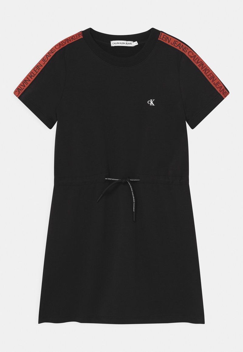 Černé bavlněné šaty s krátkým rukávem. Mají šňůrku v pase, ikonické logo na hrudi a červené značkové akcenty na rukávech.