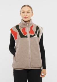 Kamizelka polarowa z wysokim kołnierzem, z abstrakcyjnymi wzorami w odcieniach pomarańczowego, zielonego i kremowego. Zamek z przodu oraz boczne kieszenie.