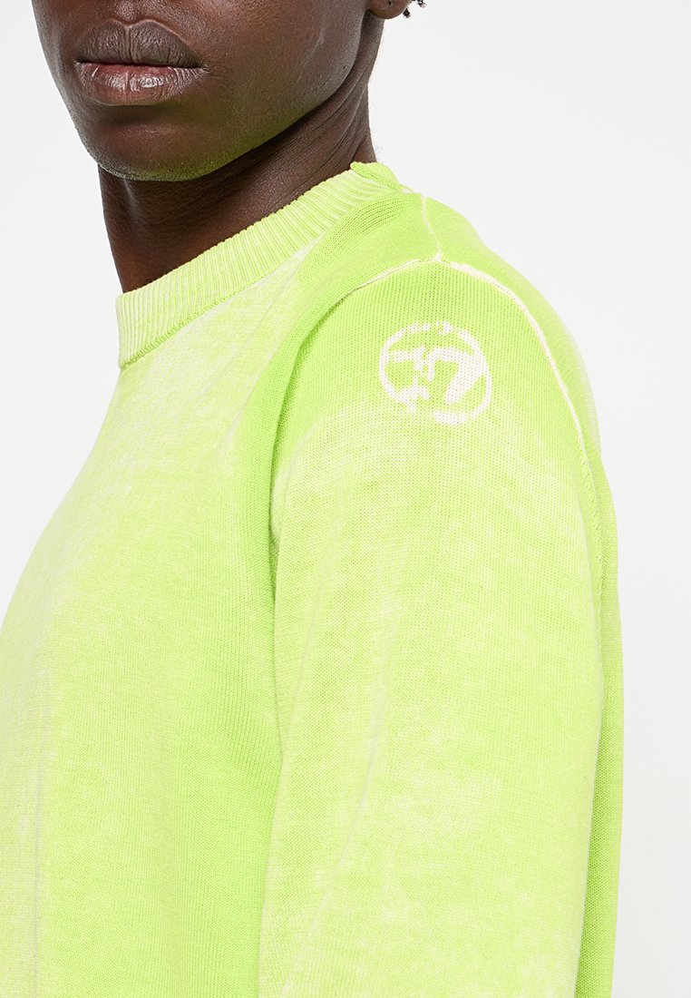 Neon grüner Pullover mit Rundhalsausschnitt, geripptem Saum und auffälligem Logodetail an der Schulter. Das Material wirkt weich mit strukturierter Oberfläche.
