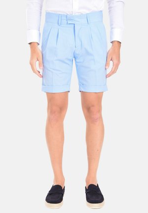 Pantaloni corti a pieghe blu chiaro con orlo risvoltato, realizzati in un tessuto liscio. Abbinati a scarpe slip-on di un blu navy scuro.
