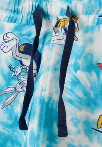 Pantalones cortos de color azul claro con un patrón de tie-dye, que cuentan con ilustraciones de dibujos animados. Fabricados con una tela suave y con cordones y cinturilla de color azul oscuro.