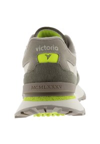Sneaker in suede grigio con accenti bianchi, logo riflettente e dettaglio del tallone verde brillante. Suola in gomma con battistrada e ammortizzazione nel tallone.
