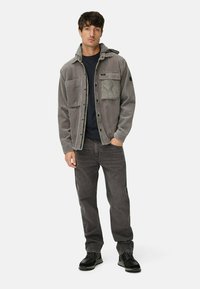 Gray corduroy jacket with a hood, featuring a chest pocket and black accents, paired with dark gray pants and black shoes.