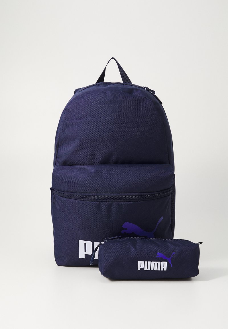 Mochila de tela azul marino con un bolsillo frontal y un estuche de lápices a juego, ambos con un logo de Puma en púrpura y texto en blanco.