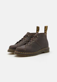 Brune lær ankle støvler med gule pull tabs, sorte gummisåler og kontrastsøm detaljer. Har tradisjonelt snøring design.
