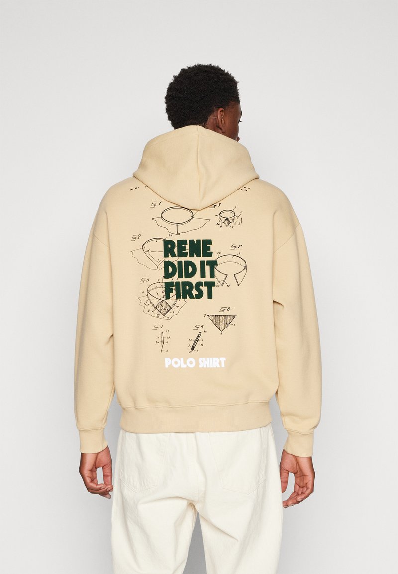 Beige hoodie met een achterkantprint met technische ontwerpen en groene tekst die zegt "RENE DID IT FIRST" boven "POLO SHIRT." Zachte stof.