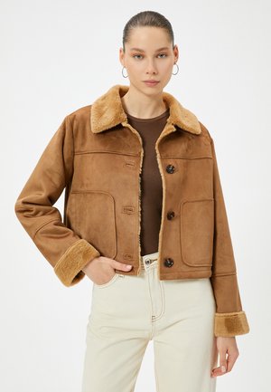 Chaqueta de ante sintético marrón con un cuello y puños de pelo en contraste. Presenta botones y dos bolsillos frontales, diseño corto.