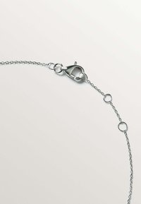 Collar de cadena de plata con cierre de langosta y eslabones circulares. La cadena tiene una textura suave y un diseño sencillo, ideal para superponer.