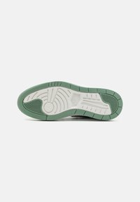 Semelle d'une chaussure de sport avec un motif d'usure vert et blanc, des motifs circulaires et linéaires, et les logos Nike et Jordan visibles au centre.