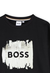 T-shirt nera con scollatura rotonda. Presenta un grande design a pennellata bianca e la parola "BOSS" in lettere nere in grassetto. Collo in cotone.