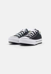 Schwarze Canvas-Sneaker mit weißen Schnürsenkeln, Gummisohlen und einer weißen Zehenkappe; hat einen hellbraunen Akzent am Kragen und schwarze Streifen.