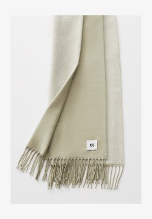 Light beige soft scarf with twisted fringe edges and a small white tag featuring a black abstract logo on a white background.
