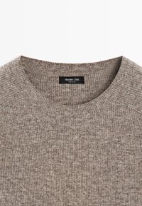 Maglione beige lavorato a maglia con colletto rotondo, texture fine e sottili variazioni di colore. Etichetta visibile all'interno con "Massimo Dutti."