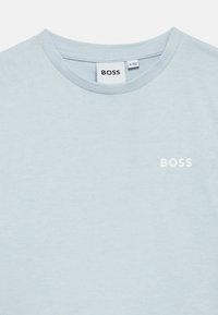 Γαλάζιο βαμβακερό T-shirt με στρογγυλή λαιμόκοψη και κοντά μανίκια. Το όνομα της μάρκας "BOSS" είναι τυπωμένο με λευκά γράμματα στο στήθος.