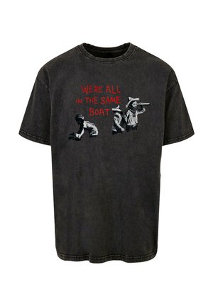 Fekete pamut póló, amelyen a "EGY HAJÓBAN VAGYUNK" felirat olvasható piros színnel, fekete és fehér grafikai részletekkel gyerekekről.