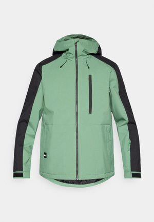 Groene en zwarte outdoorjas met capuchon, ritssluiting, een borstzak en elastische manchetten. Gemaakt van een gladde, duurzame stof.