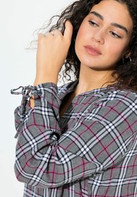 Camicia a quadri grigia con linee rosa e nere, dotata di lacci sui polsini e un collo tondo. Tessuto morbido con una vestibilità comoda e maniche lunghe.