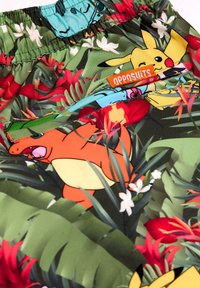 Farebné šortky s tropickým vzorom a postavičkami Pokémon. Vyrobené z ľahkej tkaniny, obsahujú vonkajšie vrecko s logom.