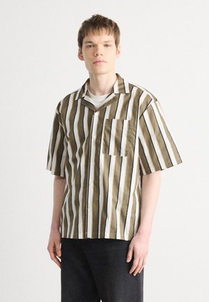 Short-sleeve shirt featuring vertical stripes in brown, white, and black, with a collar and a chest pocket. Cotton fabric with a smooth texture.