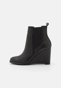 Black leather wedge ankle boots with a smooth finish, elastic side panels, a rear pull tab, and a textured rubber sole.