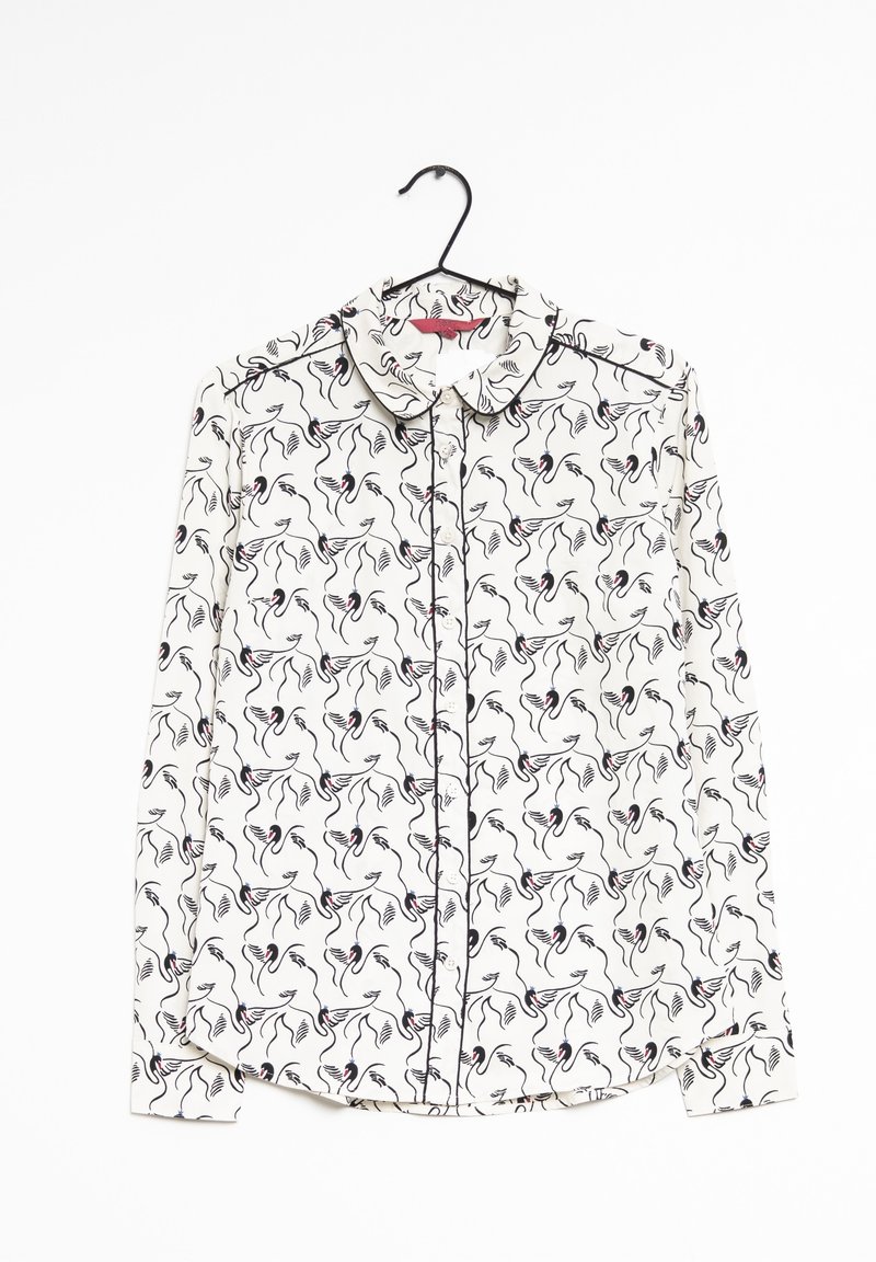 Blouse blanche à manches longues avec motif floral abstrait noir et rouge, devant boutonné, col et cintre noir sur fond blanc.