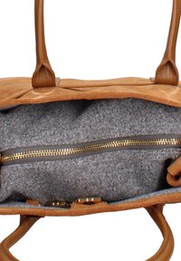 Interno di una borsa in camoscio marrone con rivestimento in feltro grigio, dotata di una tasca con cerniera dorata e dettagli in pelle color cuoio. Le maniglie sono fissate nella parte superiore.