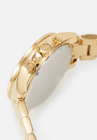 Goldfarbene analoge Uhr mit rundem Gehäuse, drei Seitentasten und einem polierten Metallarmband mit Link-Design.