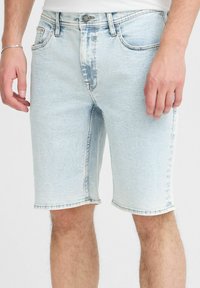 Ljust blå denimshorts med en avslappnad passform, fem fickor, fransade kanter och diskret blekning. Standard knapp- och dragkedjestängning.