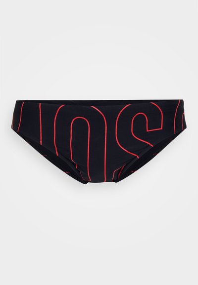 Boxer de natação preto com grandes letras em vermelho contornadas formando uma palavra parcial ao longo do tecido, exibido sobre um fundo branco.