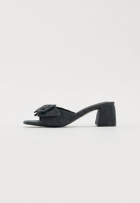 Sandal con tacco alto nero a scivolo con dettaglio di fiore in tessuto sulla cinghia, punte chiuse, tomaia testurizzata e un tacco a blocco spesso e curvo.