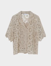Blouse beige en crochet à manches courtes avec motifs floraux hexagonaux et col cranté, présentée sur un fond blanc.