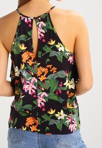 Top halter floreale con sfondo nero, caratterizzato da vivaci fiori arancioni, rosa e gialli, in tessuto leggero e dettaglio a chiave sul retro.