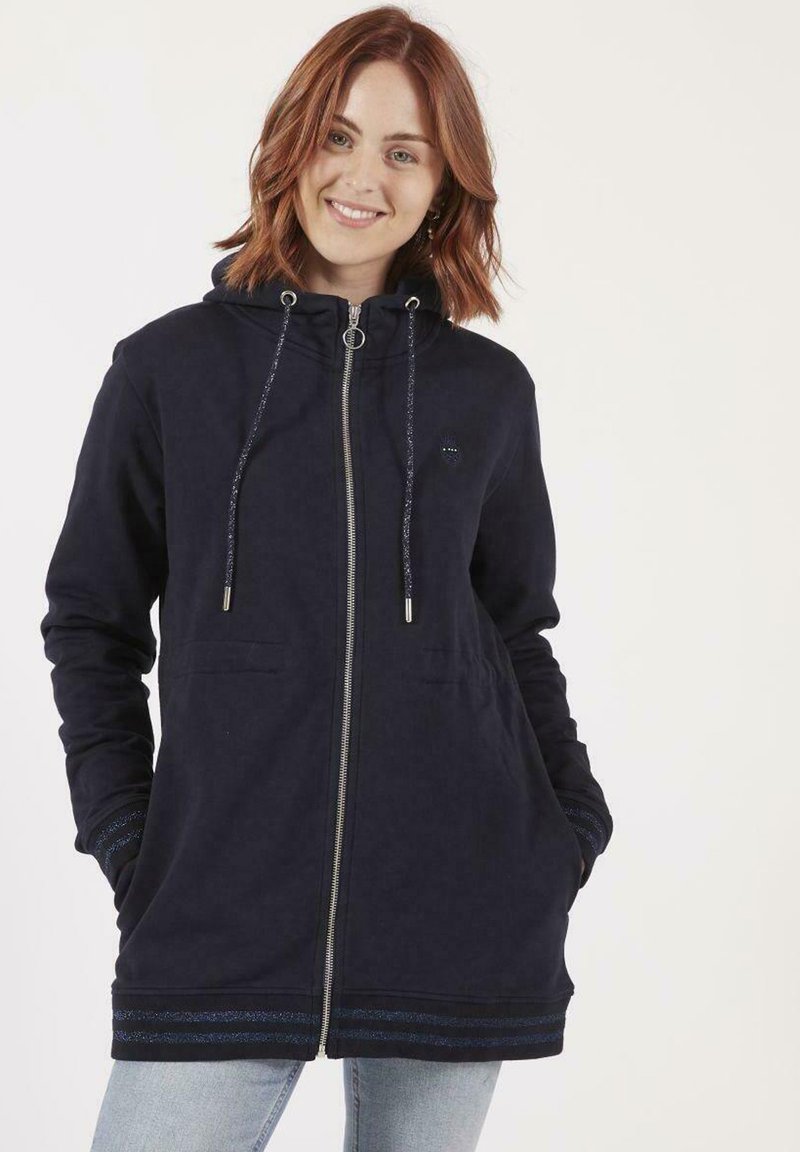 Veste à capuche navy en matériau doux avec une fermeture éclair, des poches avant et des accents rayés décoratifs aux poignets et à l'ourlet. Capuche réglable.