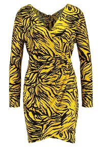 Žluté a černé šaty s dlouhým rukávem, navržené jako zavinovací, s tygřím pruhovaným vzorem a výstřihem do V s detaily na zadní zavázání.
