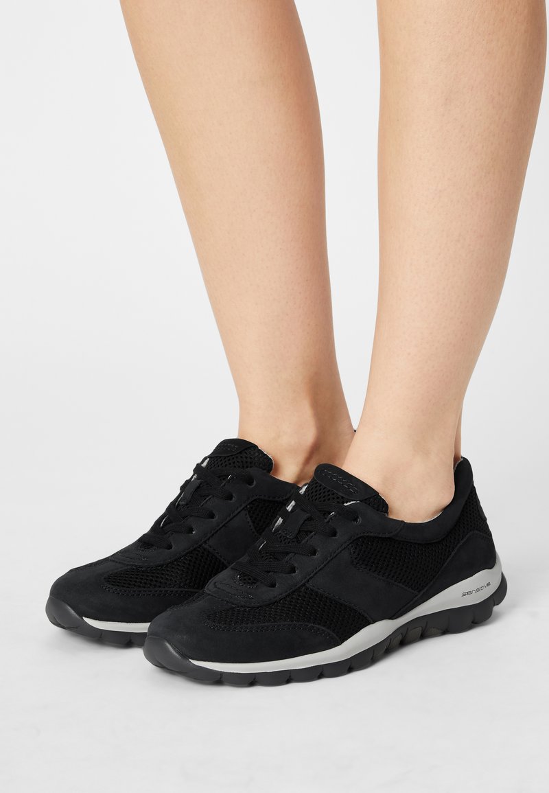Zwarte sportschoenen gemaakt van mesh en suede materialen, met een vetersluiting, textuuraccenten en een rubberen zool met demping.
