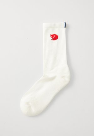 White ribbed sock with a red animal logo on the side. Made of soft material, featuring a standard crew length and blue accent at the top.