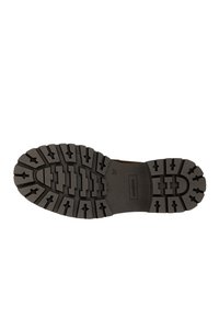 Suola di stivale in gomma nera con un motivo di battistrada spesso e vari design scanalati per trazione e durata. Logo "Sole" visibile.