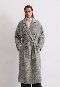 Grijs en wit gespikkelde wollen jas met een dubbele knoopsluiting, ceintuur in de taille, grote kraag en brede mouwen. Gestructureerde stof.