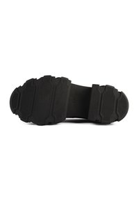 Semelle de chaussure noire avec des motifs de bande de roulement profonds et texturés, conçue pour l'adhérence et la durabilité sur diverses surfaces.