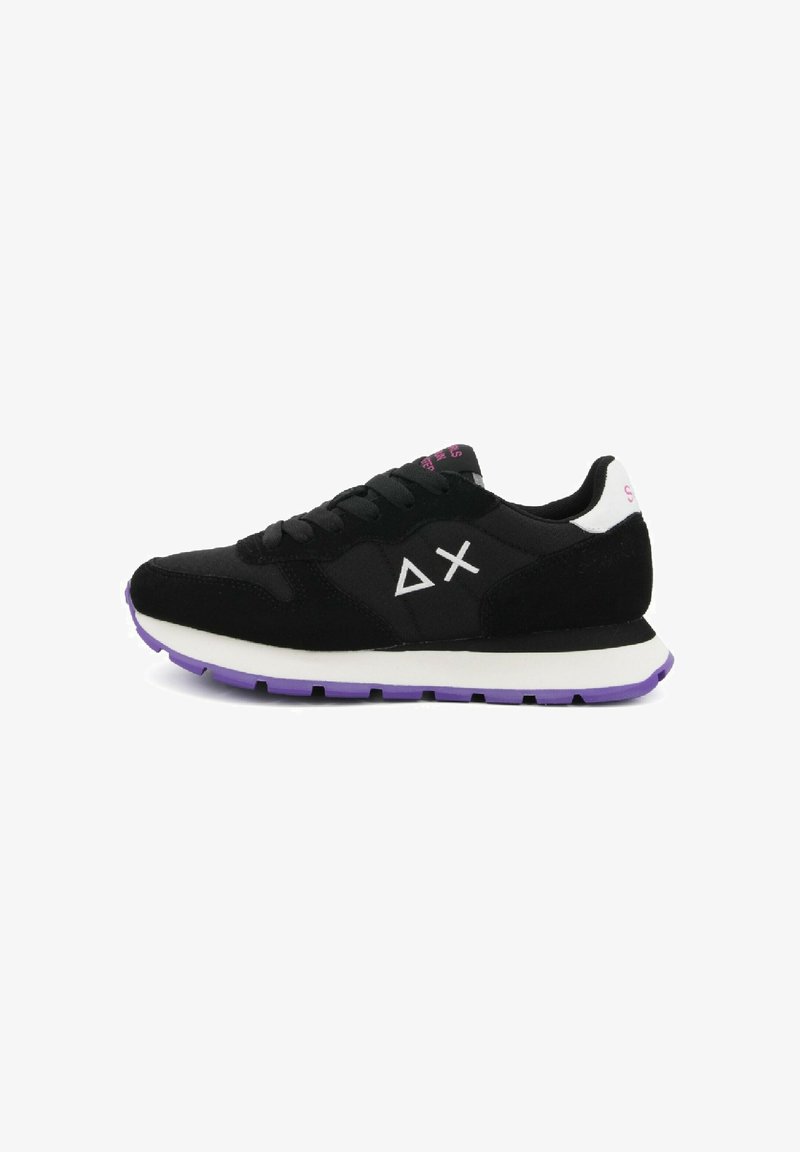 Sneaker nera con suola bianca, suola esterna viola, logo triangolare e a croce bianco sul lato e linguetta bianca sul tallone con testo rosa.