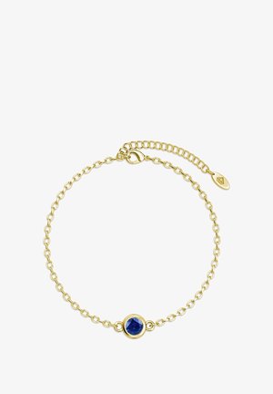 Bracciale in catena d'oro con punto focale in pietra blu rotonda, dotato di chiusura regolabile e una piccola etichetta con logo attaccata.