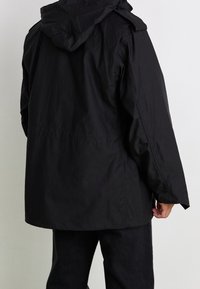 Czarna wodoodporna kurtka z kapturem, o luźnym kroju, z naszytymi ramionami oraz gładką fakturą. Prosty design z tyłu, bez ozdób.