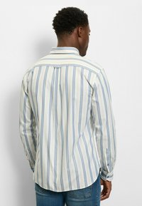 Langärmeliges Hemd mit blau-weißen vertikalen Streifen, Knopfkragen, weichem Stoff, abgerundetem Saum und knöpfbaren Manschetten.