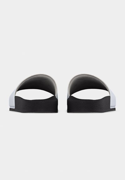 Ζευγάρι μαύρα και άσπρα σαγιονάρες, σε όψη από μπροστά, με χοντρές μαύρες σόλες και λευκές φαρδιές λουρίδες.