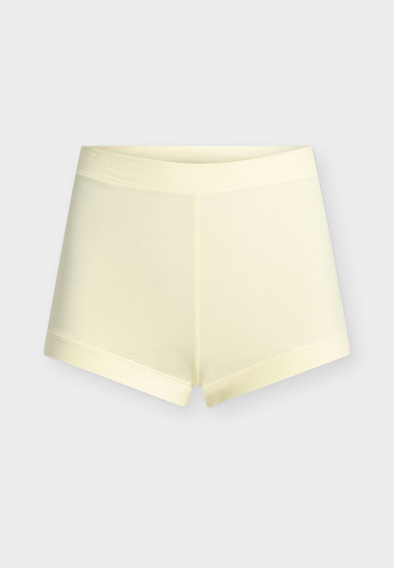 Κρεμ χρώματος, άνετα, ριψοκινδύνως εφαρμοστά σορτς με φαρδιά μέση και κοντό μήκος ποδιού, εμφανίζεται σε απλό φωτεινό φόντο.