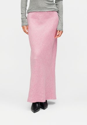 Różowa, długa dzianinowa spódnica z subtelnym, teksturowanym wzorem, zestawiona z szarą bluzką z długim rękawem i czarnymi botkami z ostrym noskiem.