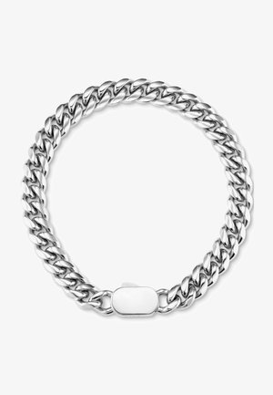 Pulsera de cadena metálica en la muñeca; color plateado con una textura suave. Un anillo a juego en el dedo presenta una pieza central redonda y texturizada.