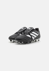 Sorte fodboldstøvler har et tekstureret læderoverdel, tre hvide striber og gummistudser for bedre greb. Indeholder et design med en enkelt tunge.